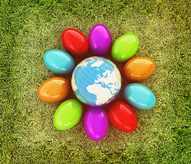 Image showing Colored Easter eggs around Earth on a green grass. 3D illustrati