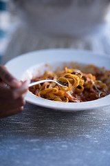 Image showing a young African American woman eating pasta