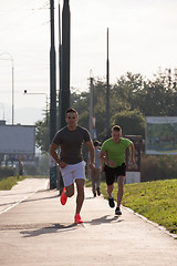 Image showing Two young men jogging through the city