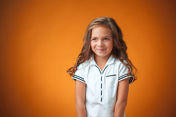 Image showing The cute cheerful little girl on orange background