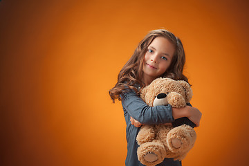 Image showing The cute cheerful little girl on orange background