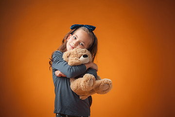 Image showing The cute cheerful little girl on orange background