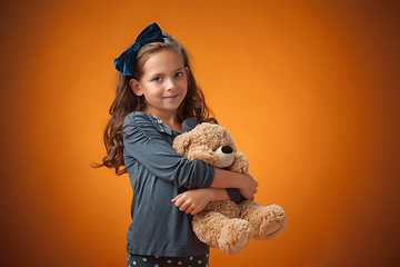 Image showing The cute cheerful little girl on orange background