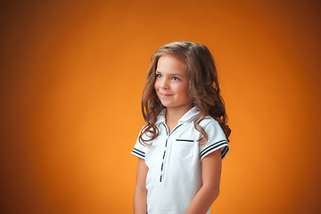 Image showing The cute cheerful little girl on orange background