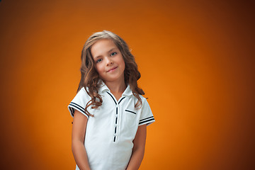 Image showing The cute cheerful little girl on orange background