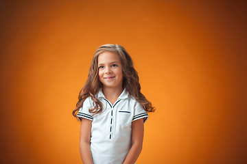 Image showing The cute cheerful little girl on orange background