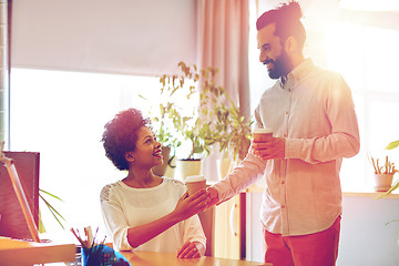 Image showing happy man bringing coffee to woman in office