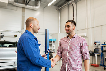 Image showing auto mechanic and man shaking hands at car shop