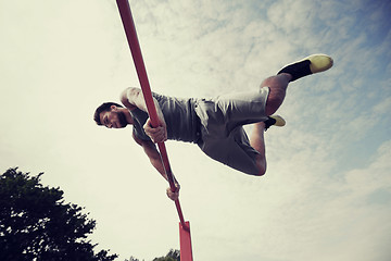 Image showing young man exercising on horizontal bar outdoors