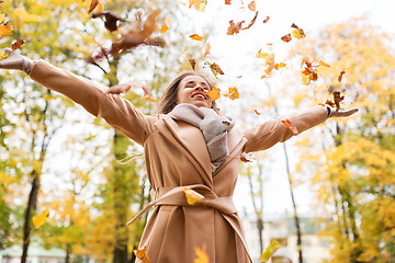 Image showing happy woman having fun with leaves in autumn park