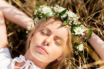 Image showing happy woman in wreath of flowers lying on straw