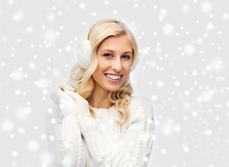 Image showing smiling young woman in winter earmuffs and sweater