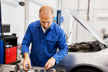 Image showing mechanic man with wrench repairing car at workshop