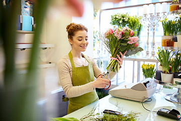 Image showing smiling florist woman making bunch at flower shop