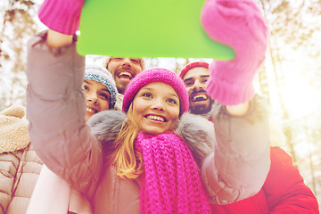 Image showing smiling friends with tablet pc in winter forest