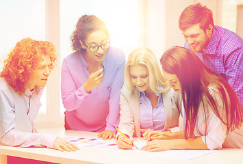 Image showing smiling creative team looking over clothes designs