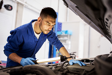 Image showing mechanic man with lamp repairing car at workshop