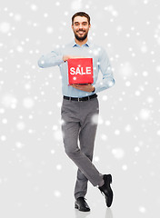Image showing smiling man with red sale sign over snow