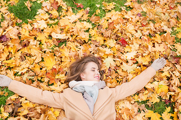 Image showing beautiful happy woman lying on autumn leaves