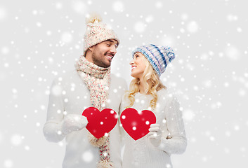 Image showing smiling couple in winter clothes with red hearts