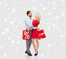 Image showing happy couple with red shopping bags over snow