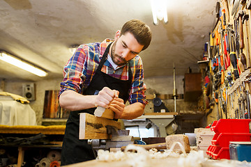 Image showing carpenter working with plane and wood at workshop