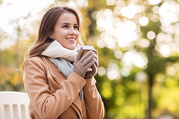 Image showing happy young woman drinking coffee in autumn park