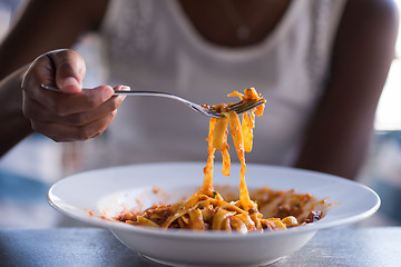 Image showing a young African American woman eating pasta