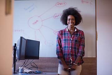 Image showing African American woman writing on a chalkboard in a modern offic