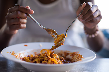 Image showing a young African American woman eating pasta