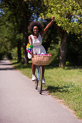 Image showing pretty young african american woman riding a bike in forest