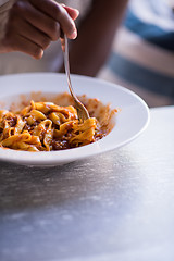 Image showing a young African American woman eating pasta