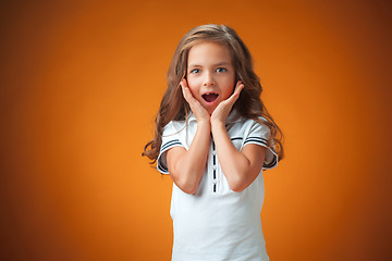 Image showing The cute surprised little girl on orange background