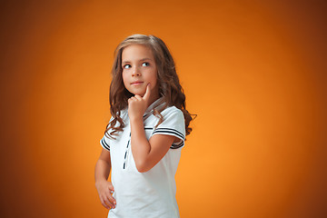 Image showing The cute thoughtful little girl on orange background