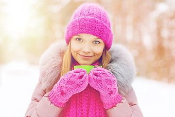 Image showing smiling young woman with cup in winter forest