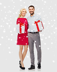 Image showing happy couple with christmas gift boxes over snow