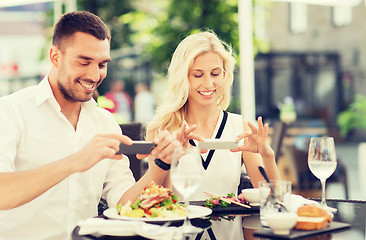 Image showing happy couple with smatphone photographing food