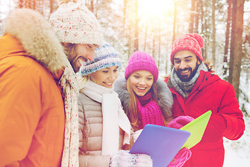 Image showing smiling friends with tablet pc in winter forest