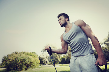 Image showing young man exercising with expander in summer park