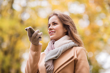 Image showing woman recording voice on smartphone in autumn park