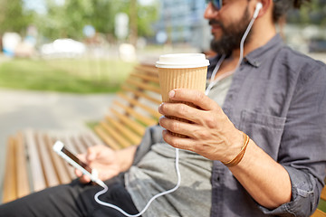 Image showing man with earphones and smartphone drinking coffee