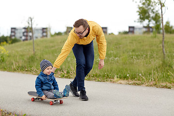Image showing happy father and little son riding on skateboard