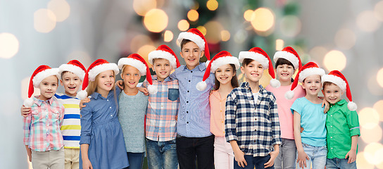 Image showing happy smiling children in santa hats hugging