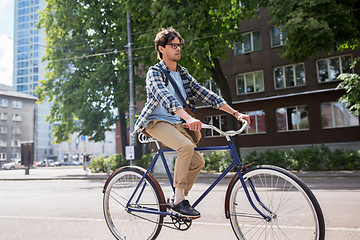 Image showing young hipster man with bag riding fixed gear bike