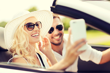 Image showing happy couple in car taking selfie with smartphone