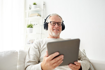 Image showing senior man with tablet pc and headphones at home