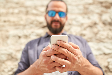 Image showing close up of man with smartphone at stone wall