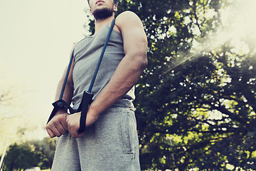 Image showing young man exercising with expander in summer park