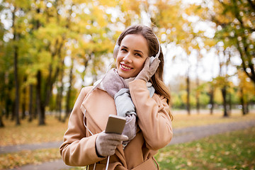 Image showing woman with smartphone and earphones in autumn park