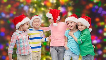 Image showing happy little children in santa hats hugging